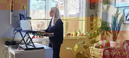 A woman at her home-office standing desk and laptop